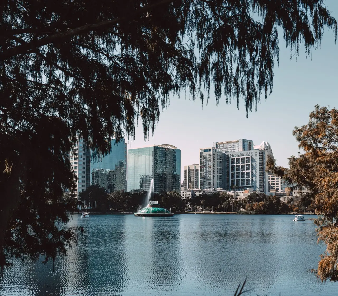 Downtown Orlando skyline seen across Lake Eola, framed by live oak canopy